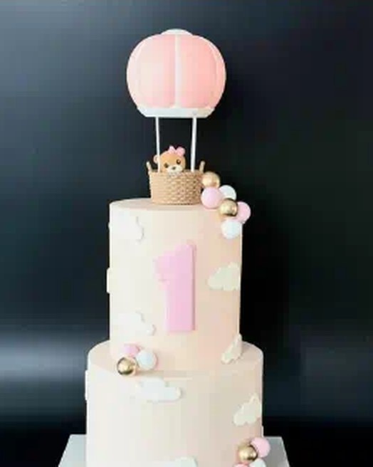 Pastel first birthday cake with hot air balloon topper