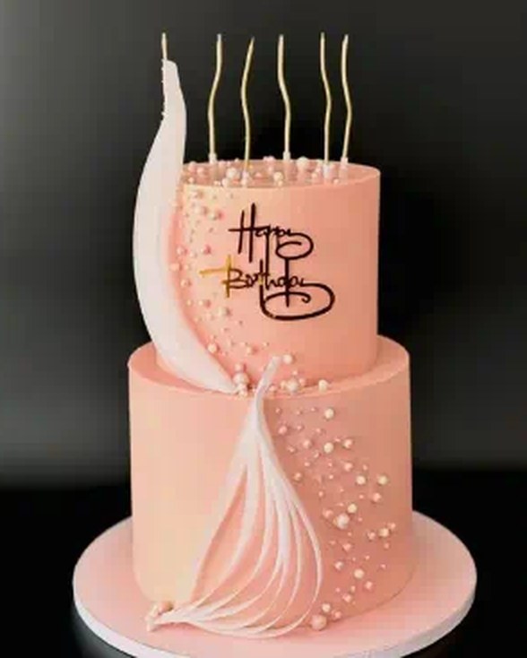 Two-tier blush pink birthday cake with white sugar feather and gold lettering